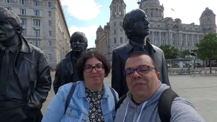 ana y victor de verviajando delante de la estatua de los beatles
